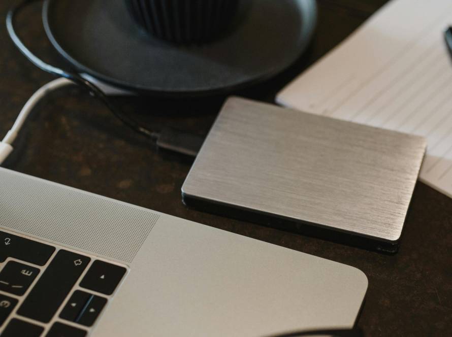 Free Closeup of an external hard drive connected to a laptop with a USB cable on a desk. Stock Photo