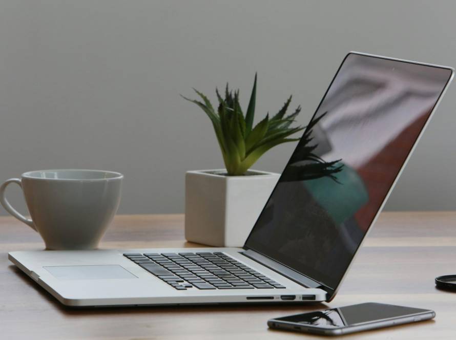 Free Minimalist home office desk with laptop, smartphone, and plant for a modern work environment. Stock Photo